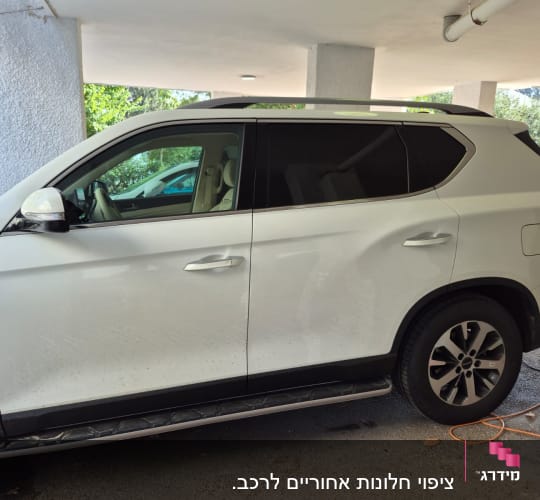 רכב חונה מתחת למבנה עם חלונות כהים